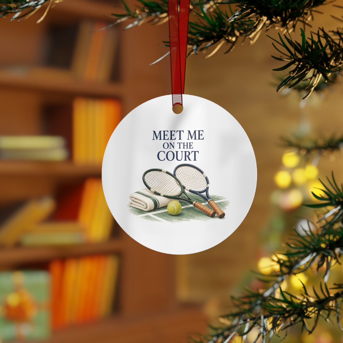 Lifestyle view of the round ornament with tennis artwork and red hanging ribbon.