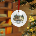 Lifestyle view of the round ornament with hiking artwork and red hanging ribbon.