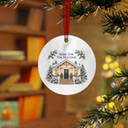 Lifestyle view of the round ornament with winter house artwork and red hanging ribbon.